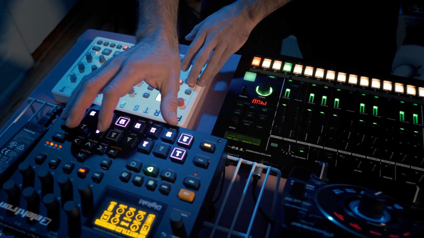 Hands working a sampler and drum machine mid-set